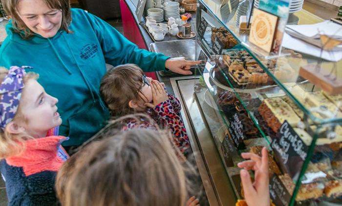 Mother and children looking at cakes on display in cafe